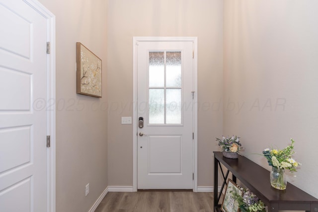 doorway to outside featuring wood finished floors and baseboards
