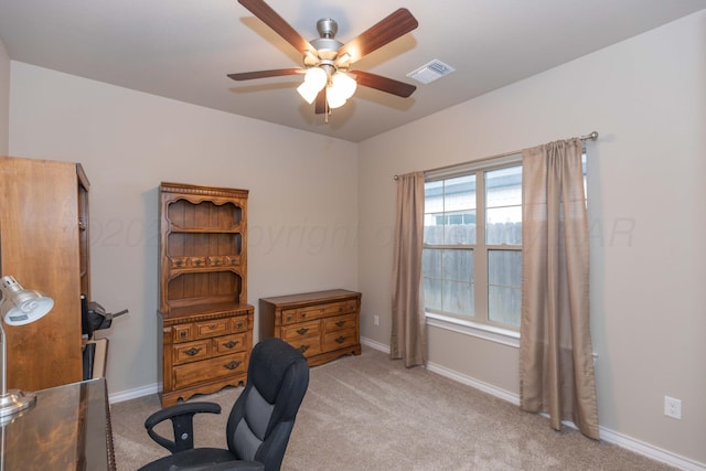 carpeted office space featuring a ceiling fan and baseboards
