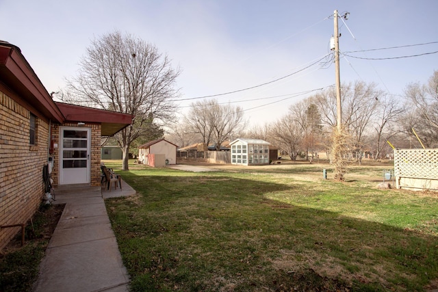 view of yard with a storage shed, an outdoor structure, and fence