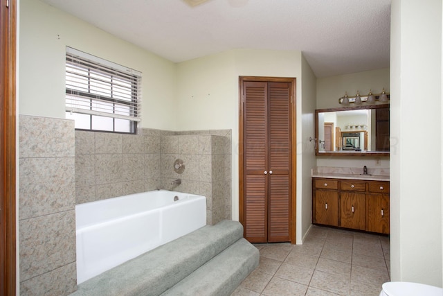 bathroom with vanity, a closet, a textured ceiling, tile patterned floors, and a bath