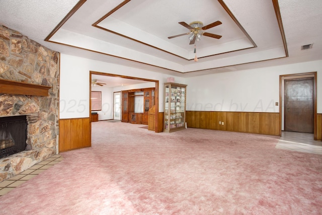 unfurnished living room featuring a wainscoted wall, visible vents, a ceiling fan, and a tray ceiling