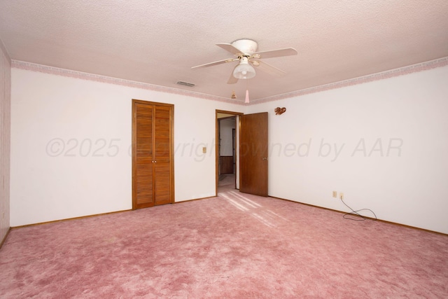 empty room featuring visible vents, carpet flooring, a textured ceiling, and a ceiling fan