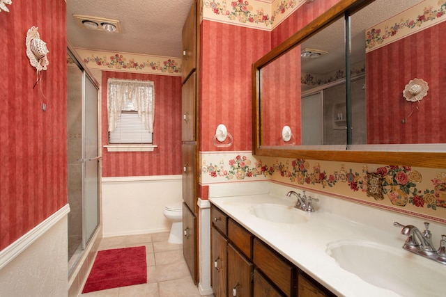 bathroom featuring a sink, a textured ceiling, and wallpapered walls