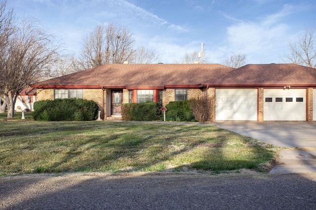 ranch-style home with roof with shingles, concrete driveway, a front yard, an attached garage, and brick siding