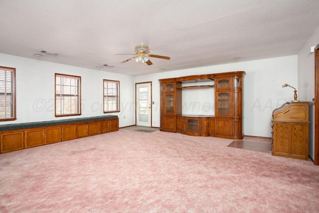 unfurnished room featuring a wealth of natural light, carpet flooring, a textured ceiling, and a ceiling fan