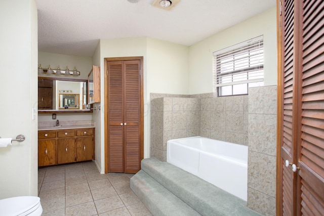 full bath featuring vanity, a bath, a closet, tile patterned floors, and toilet