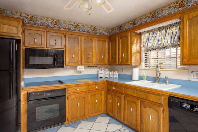 kitchen with brown cabinets, black appliances, a ceiling fan, a sink, and light tile patterned floors