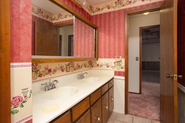 full bath with double vanity, wallpapered walls, baseboards, and a sink