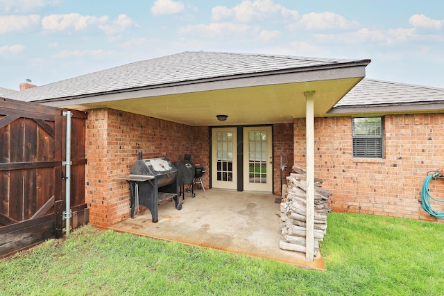 rear view of property featuring a gate, brick siding, roof with shingles, and a patio