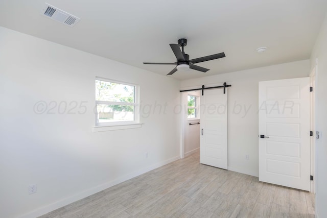 3807 Hancock St, Amarillo, TX 79109 - unfurnished bedroom with a barn door, light wood-style floors, baseboards, and ceiling fan