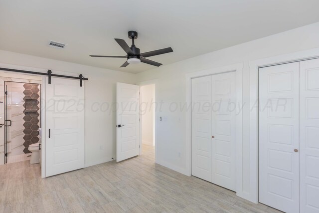 3807 Hancock St, Amarillo, TX 79109 - unfurnished bedroom with a barn door, light wood finished floors, multiple closets, baseboards, and a ceiling fan