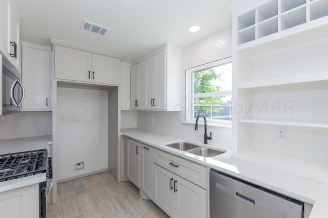 3807 Hancock St, Amarillo, TX 79109 - kitchen featuring open shelves, appliances with stainless steel finishes, a sink, light wood finished floors, and backsplash