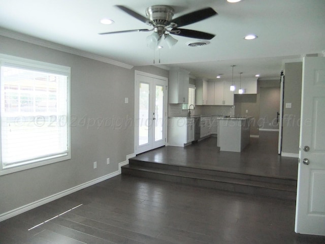 interior space with a wealth of natural light, french doors, white cabinetry, and a kitchen island