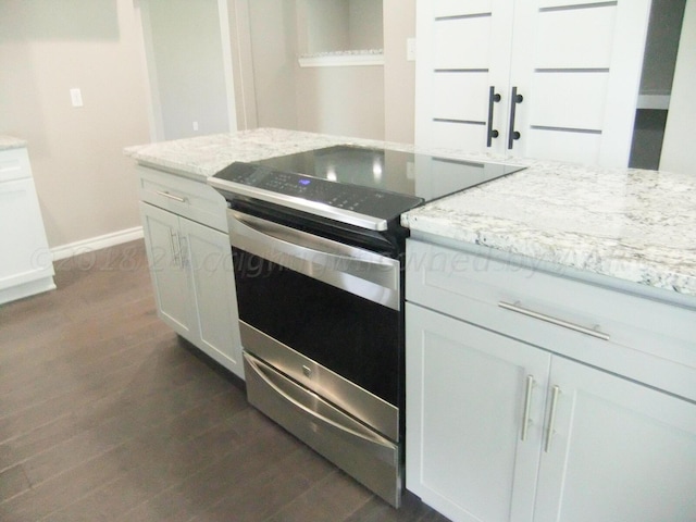 kitchen with dark wood-type flooring, stainless steel electric range, and white cabinets