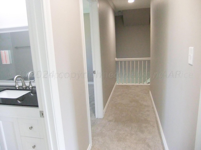 hallway with light colored carpet and sink