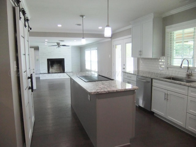 kitchen with a barn door, light stone countertops, white cabinetry, and sink