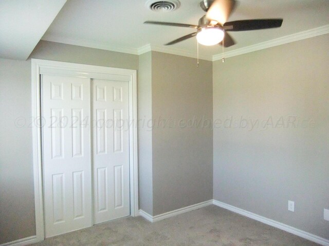 unfurnished bedroom featuring a closet, light colored carpet, ceiling fan, and crown molding