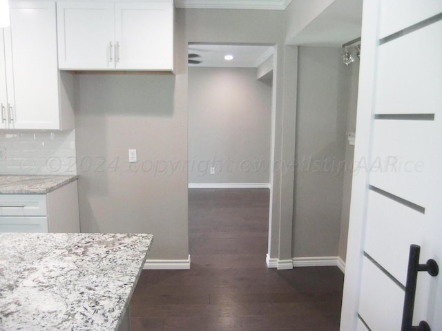 kitchen with dark wood-type flooring, light stone countertops, decorative backsplash, and white cabinets