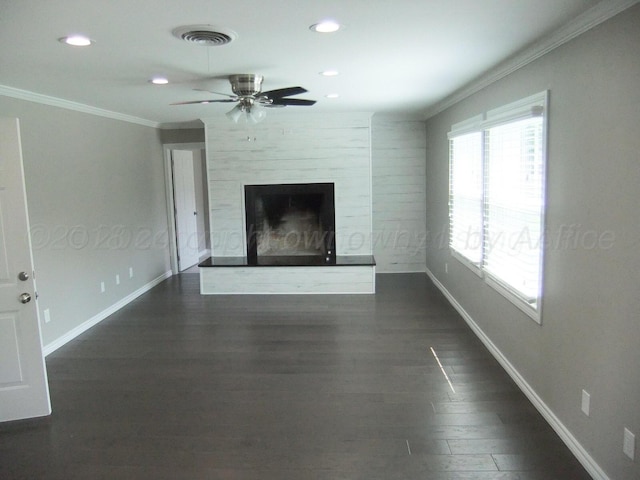 unfurnished living room with ornamental molding, a large fireplace, dark wood-type flooring, and ceiling fan