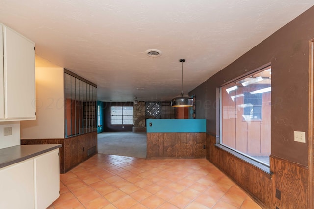 6011 Hatfield Cir, Amarillo, TX 79109 - unfurnished dining area featuring wooden walls, wainscoting, light tile patterned floors, and light colored carpet