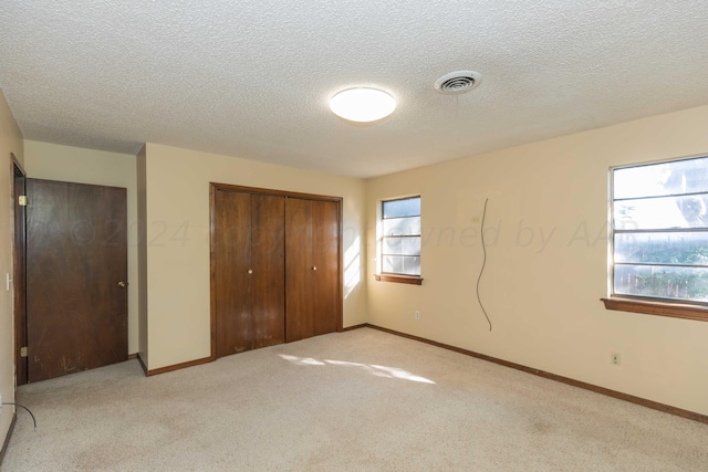 6011 Hatfield Cir, Amarillo, TX 79109 - unfurnished bedroom with a closet, multiple windows, light carpet, and a textured ceiling