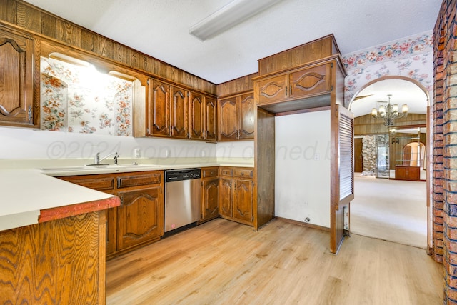 kitchen with light wood-type flooring, stainless steel dishwasher, a textured ceiling, a notable chandelier, and wood walls