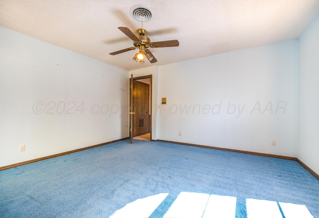 carpeted empty room featuring ceiling fan and a textured ceiling