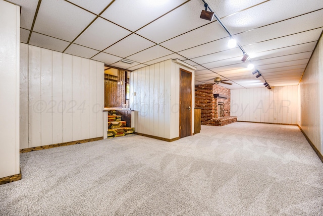 additional living space featuring carpet flooring, wooden walls, ceiling fan, and a brick fireplace