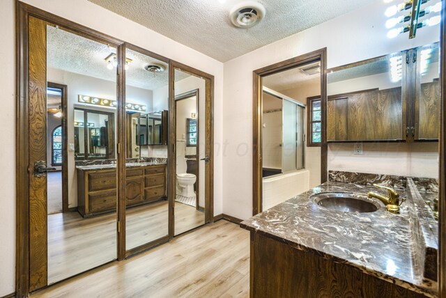 bathroom with hardwood / wood-style floors, a textured ceiling, toilet, and an enclosed shower