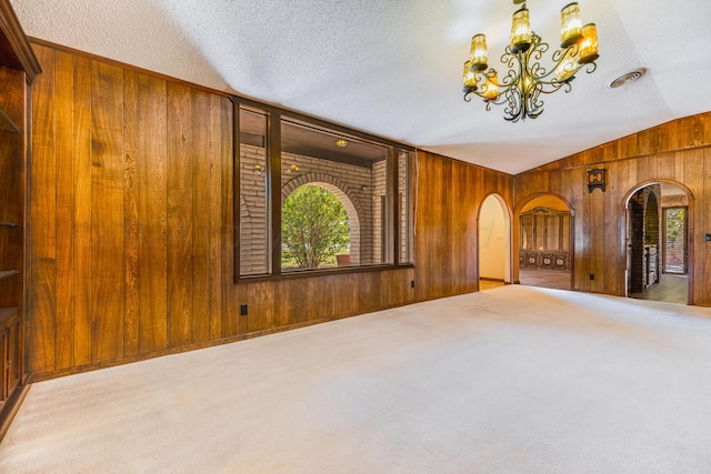 interior space with wood walls, a healthy amount of sunlight, a textured ceiling, and vaulted ceiling