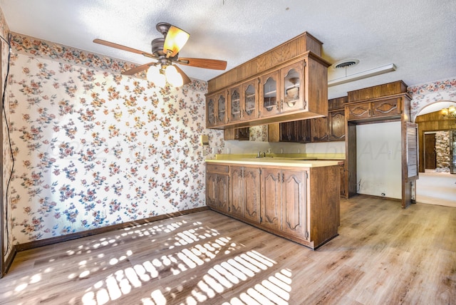 kitchen featuring ceiling fan, light hardwood / wood-style floors, kitchen peninsula, and a textured ceiling