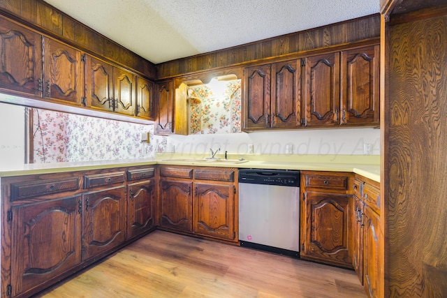 kitchen featuring stainless steel dishwasher, light hardwood / wood-style floors, sink, and a textured ceiling