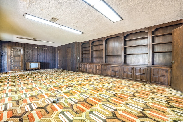 interior space featuring a textured ceiling and wooden walls