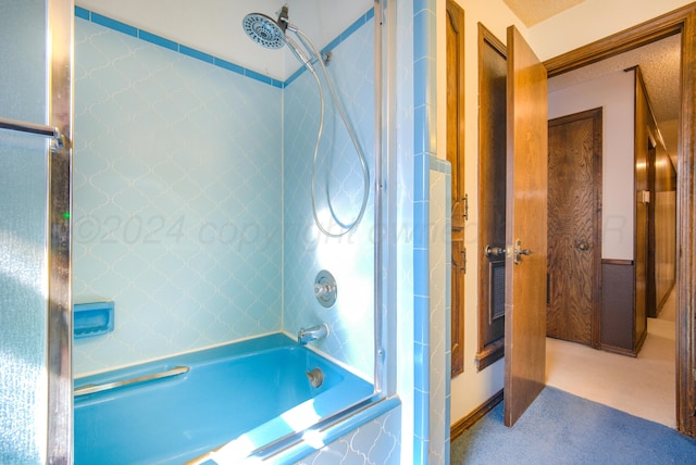 bathroom with a textured ceiling and tiled shower / bath