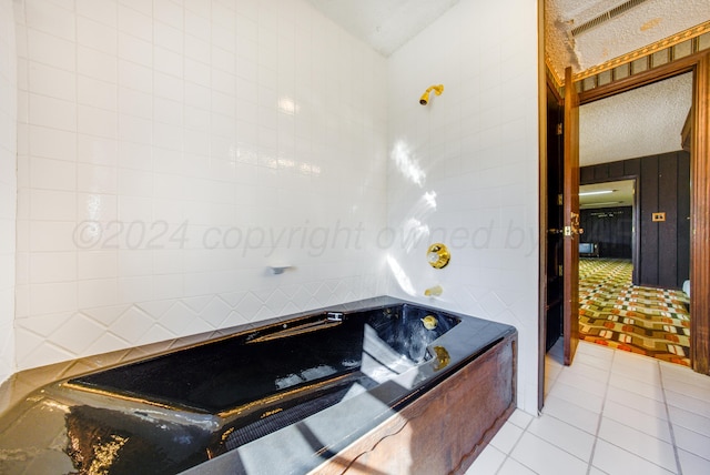 bathroom featuring tile patterned floors, a bathtub, and a textured ceiling