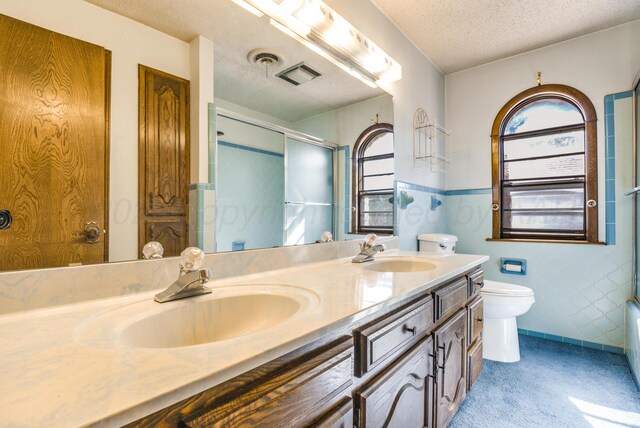 bathroom featuring vanity, a healthy amount of sunlight, a textured ceiling, and toilet