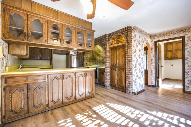 kitchen with a textured ceiling, ceiling fan, sink, light hardwood / wood-style flooring, and stainless steel electric range