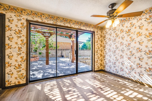 spare room with ceiling fan, plenty of natural light, wood-type flooring, and a textured ceiling