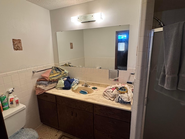 bathroom with a shower with door, vanity, a textured ceiling, and toilet