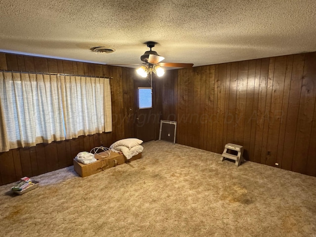 spare room with carpet flooring, a textured ceiling, and wooden walls