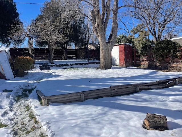 yard layered in snow featuring a storage unit