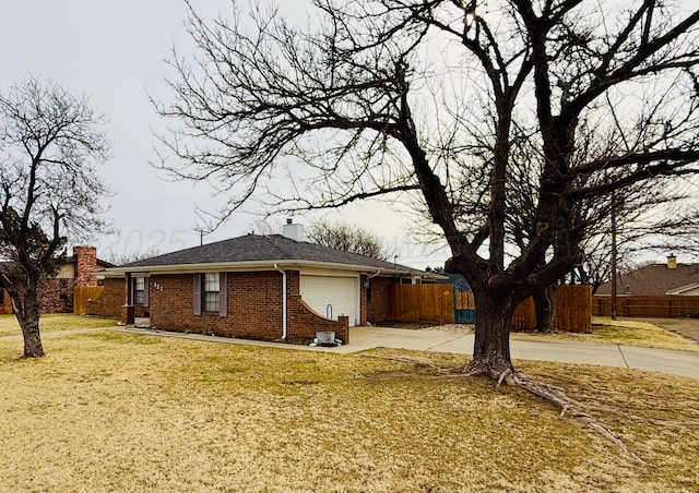 view of side of property featuring an attached garage, brick siding, fence, a yard, and a chimney