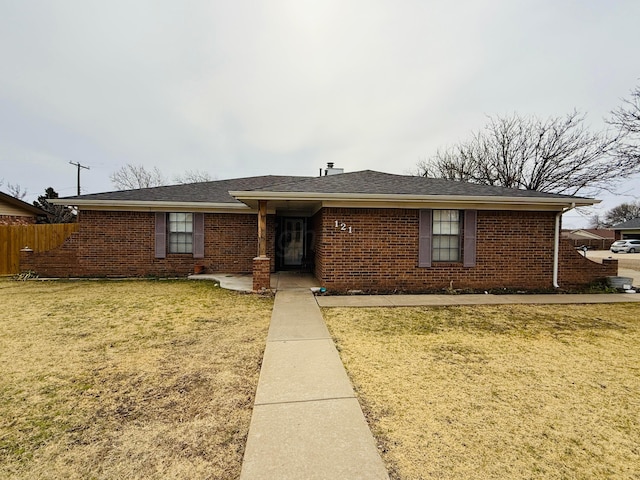 single story home featuring brick siding, fence, and a front lawn