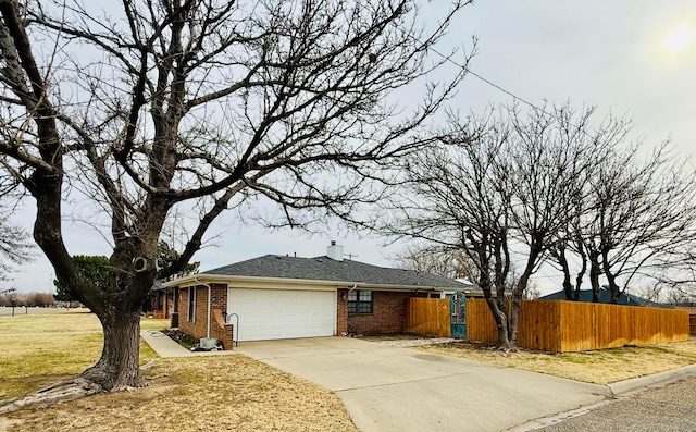 view of property exterior with an attached garage, brick siding, fence, a yard, and driveway