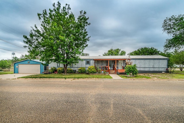 manufactured / mobile home featuring an outbuilding, a garage, a front lawn, and a porch