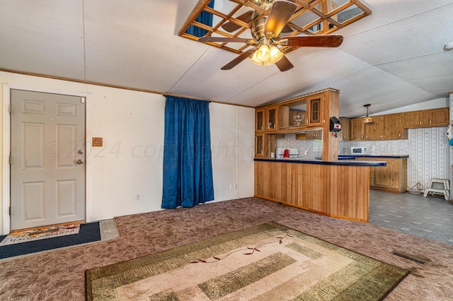 kitchen featuring kitchen peninsula, dark colored carpet, lofted ceiling, and ceiling fan