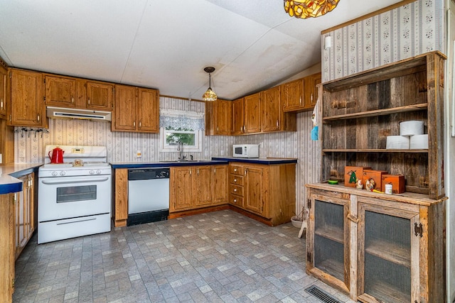 kitchen with pendant lighting, white appliances, sink, and vaulted ceiling