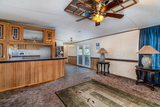 kitchen featuring wood walls, ceiling fan, a textured ceiling, and sink