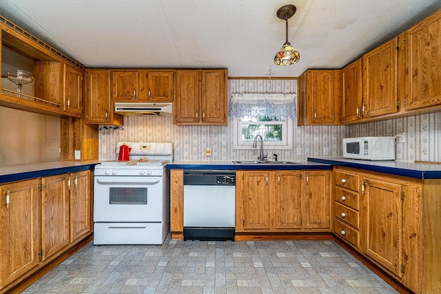 kitchen featuring pendant lighting, white appliances, sink, and a textured ceiling