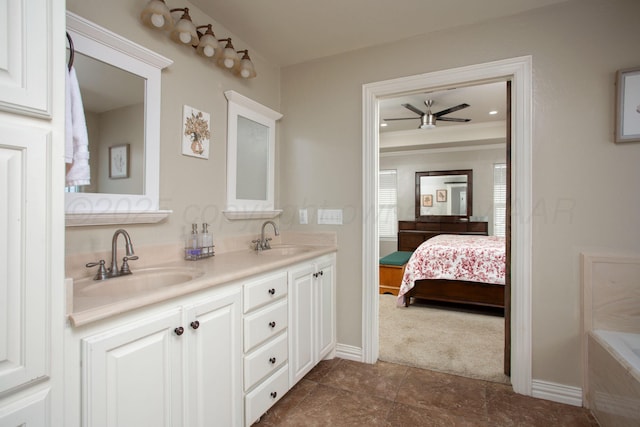 ensuite bathroom with ensuite bath, a ceiling fan, a sink, and baseboards